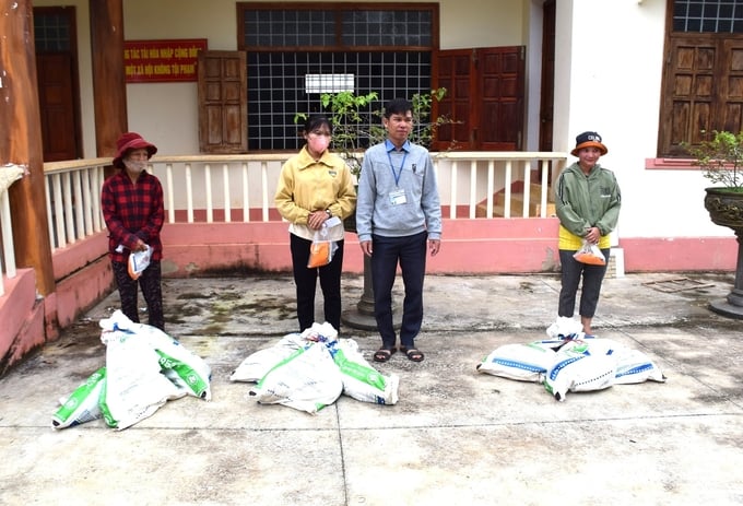 Anh Đinh Giang Sang (đứng giữa) vui lây với sự phấn khởi của những hộ được nhận heo giống. Ảnh: V.Đ.T.