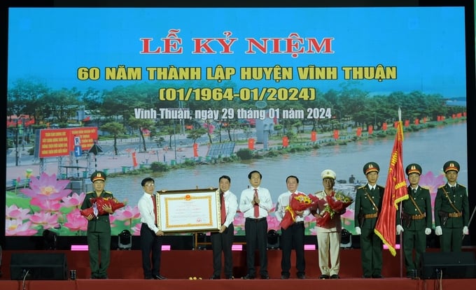 Ông Đỗ Thanh Bình, Bí thư Tỉnh ủy tỉnh Kiên Giang (thứ 4 từ trái qua) thừa ủy quyền Chủ tịch nước trao Huân chương Lao động hạng Nhất cho Đảng bộ, chính quyền và nhân dân huyện Vĩnh Thuận. Ảnh: Diễm Trang.